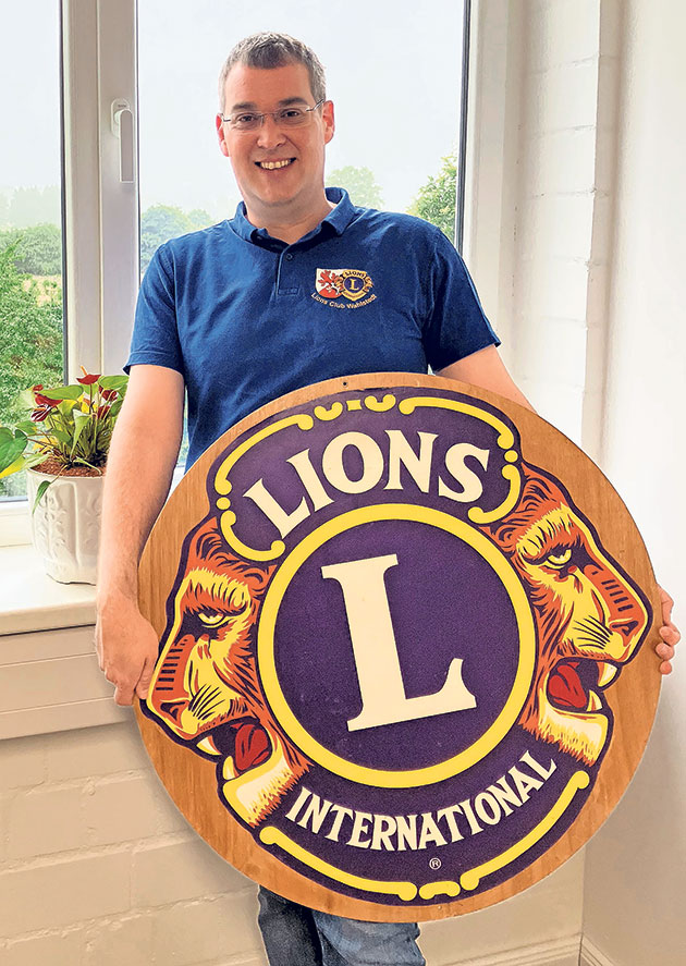 Mann mit Lions Club-Logo Person mit Lions Club-Schild neben einem Fenster