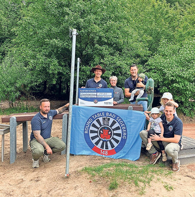 Spendenübergabe im Freien durch Round Table Gruppe mit Scheck und Round Table Banner im Freien