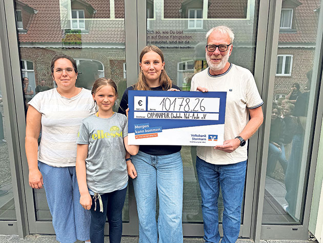 Vier Personen halten einen großen Spendenscheck.