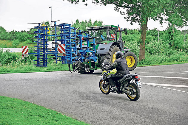 Traktor und Motorrad auf einer Landstraße Traktor mit Anbaugerät, Motorrad auf Landstraße.