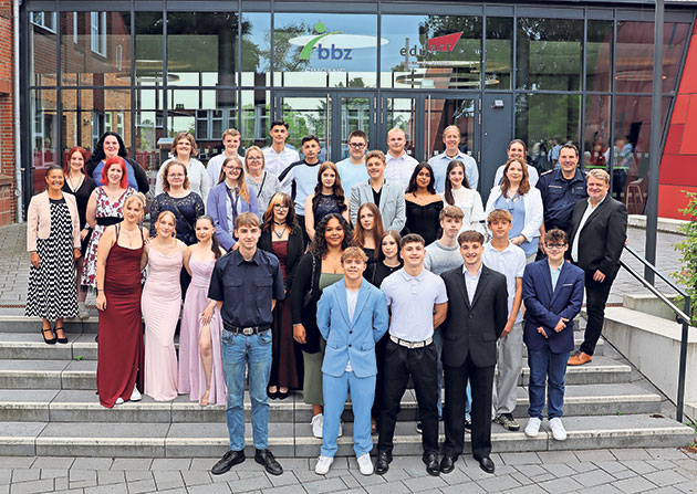 Gruppenfoto von Absolventen auf einer Treppe vor einem Gebäude.