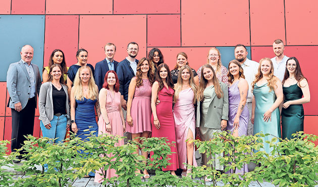 Gruppe posiert vor einer farbigen Wand. Gruppe von Menschen in eleganter Kleidung vor roter Wand.