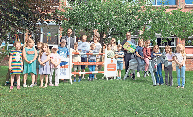 Kindergruppe mit Bauspargeldern auf der Wiese Gruppe von Kindern und Erwachsenen auf einer Wiese.