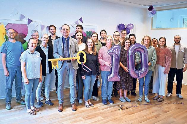 Jubiläumsfeier mit einem großen Schlüssel Gruppe feiert Jubiläum mit Luftballons in Raum