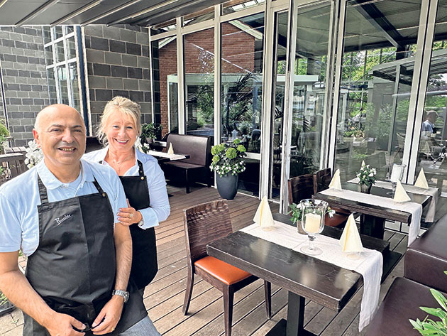 Lächelnde Menschen im Außenbereich eines Restaurants. Zwei lächelnde Personen in einem Restaurant.
