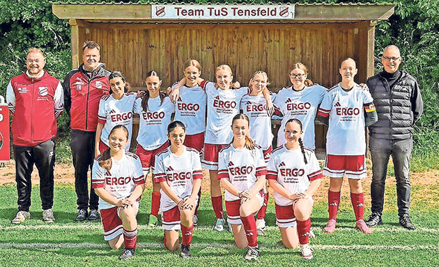 Frauenfußballteam und Trainer posieren auf dem Rasen. Fußballfrauenmannschaft mit Trainern auf dem Spielfeld.