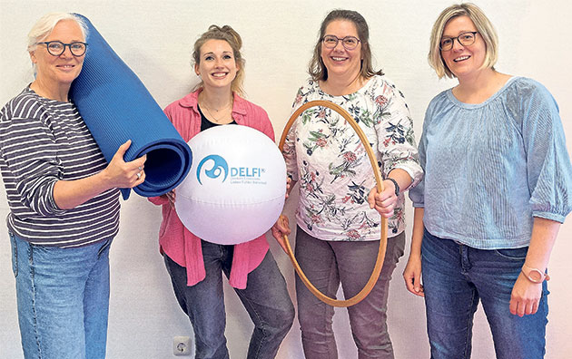 Frauen mit Gymnastikzubehör posieren für Foto Vier Frauen mit Matten und Sportgerät vor hellem Hintergrund.