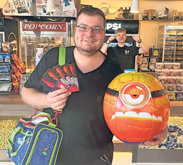 Kinobesucher freut sich über Preise Mann mit Ballon und Snacktickets im Kino.