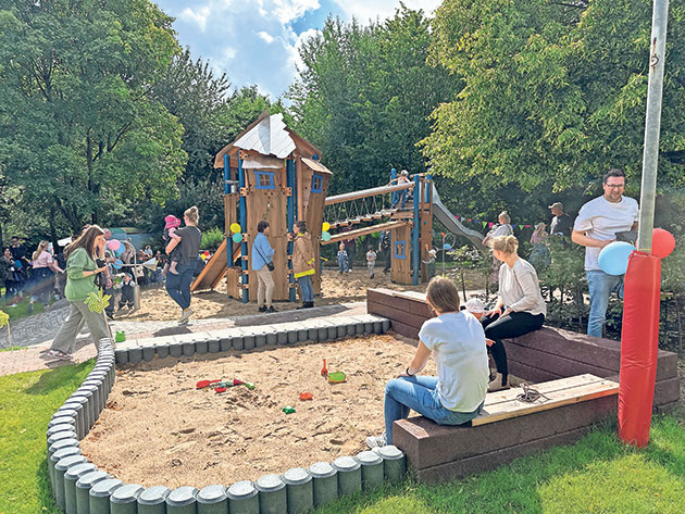Kinder spielen auf einem belebten Spielplatz mit Klettergerüst.