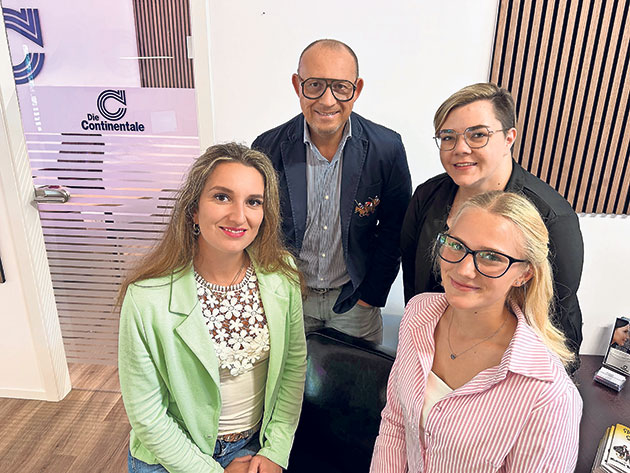 Gruppe von vier Menschen posiert im Büro.