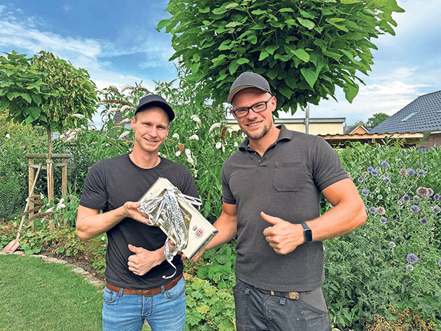 Männer mit Geschenk im Garten Zwei Männer im Garten halten ein silbernes Geschenk.