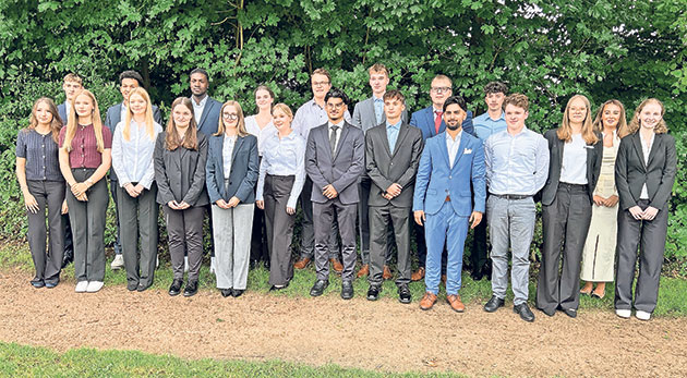 Gruppe von 19 jungen Erwachsenen in formeller Kleidung im Freien.