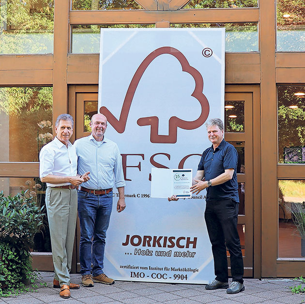 FSC-Zertifikat-Verleihung an Jorkisch Drei Männer vor einem FSC-Banner mit Zertifikat.