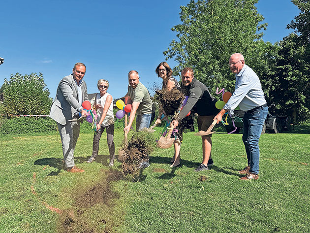 Feierlicher Spatenstich im Park Gruppe feiert Spatenstich mit bunten Schaufeln.