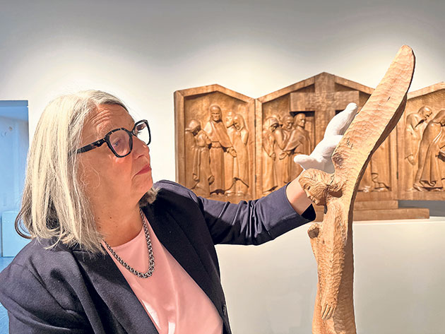 Kunstinteressierte begutachtet Holzkunstwerk Frau betrachtet Holzskulptur in einer Galerie.
