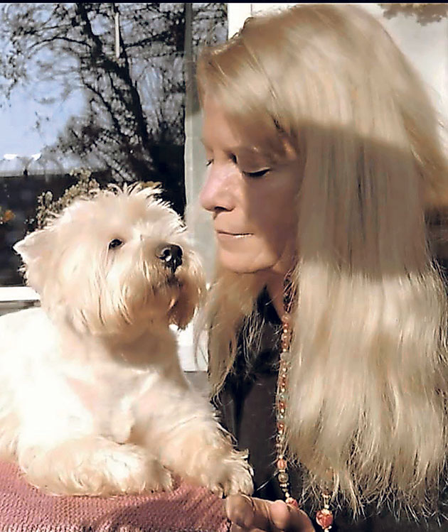 Frau und Hund blicken sich liebevoll an Frau mit langem Haar blickt liebevoll auf einen weißen Hund.