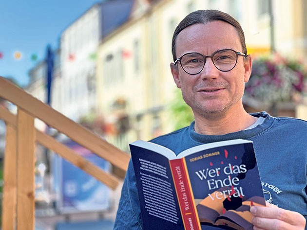 Mann liest ein Buch in einem gemütlichen Außenbereich.