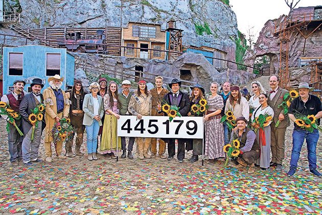 Theaterensemble feiert beeindruckende Besucherzahl Gruppe mit Nummernschild 445179 und Sonnenblumen.