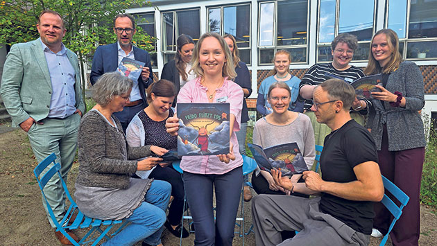Buchvorstellung im Freien mit mehreren Personen Gruppe von Menschen mit Buch vor Gebäude