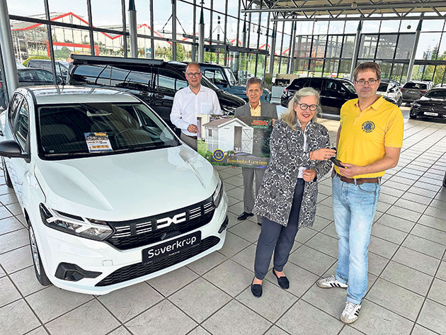Vier Personen bei der Autoübergabe im Autohaus.