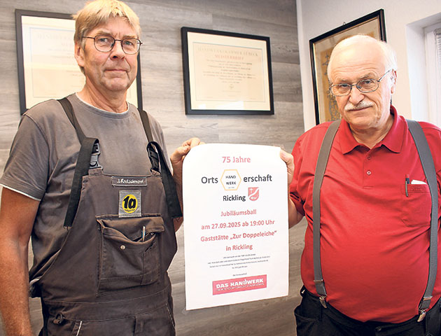 Zwei Männer halten ein Plakat für den Jubiläumsball.