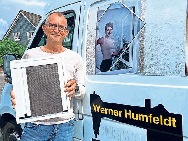 Mann hält Insektenschutzrahmen vor Lieferwagen.