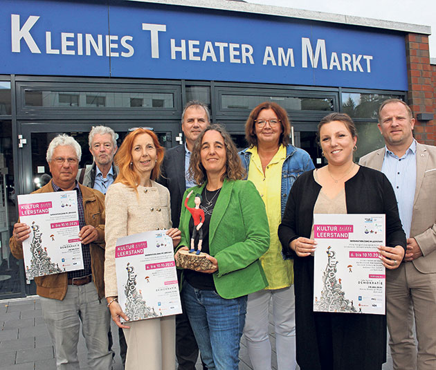 Gruppe vor dem Kleinen Theater am Markt mit Plakaten.