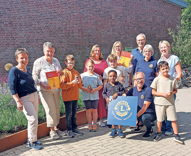 Übergabe von Urkunden an Kinder im Freien Gruppe von Erwachsenen und Kindern mit Urkunden und einem Banner