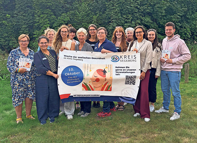 Gruppenfoto für seelische Gesundheitswoche im Kreis Segeberg Gruppe posiert mit Banner über seelische Gesundheit im Freien.