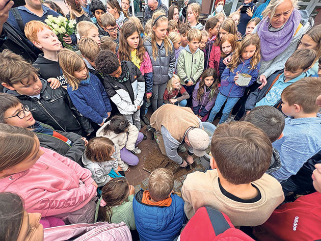 Kinder bei der Zeremonie im Freien versammelt Kinder versammeln sich um eine Person bei einer Zeremonie im Freien.