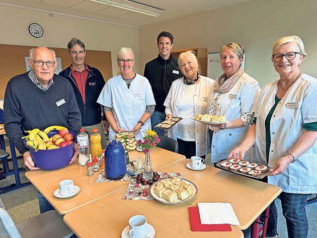 Lächelnde Gruppe mit Snacks im Gemeinschaftsraum Gruppe von Menschen lächelt in einem Raum mit Snacks.