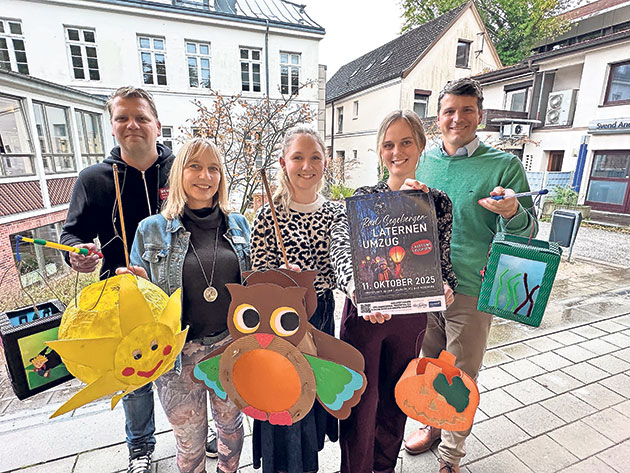 Fünf Personen mit Laternen und Plakat für Laternenumzug.