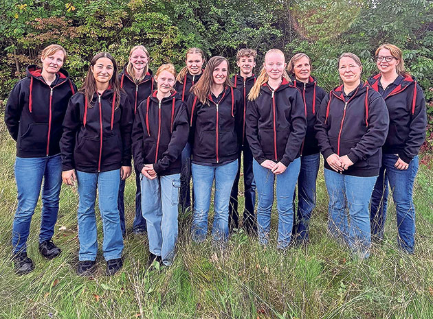 Frauen in schwarzen Hoodies im Freien Eine Gruppe von zwölf Frauen in identischen schwarzen Hoodies.