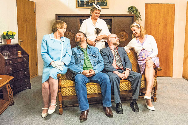 Fünf Personen auf einem Sofa in einem Wohnzimmer.