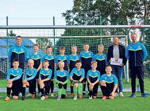 Jugendteam im Fußballtrikot vor dem Tor Jugend-Fußballmannschaft vor einem Tor posiert.