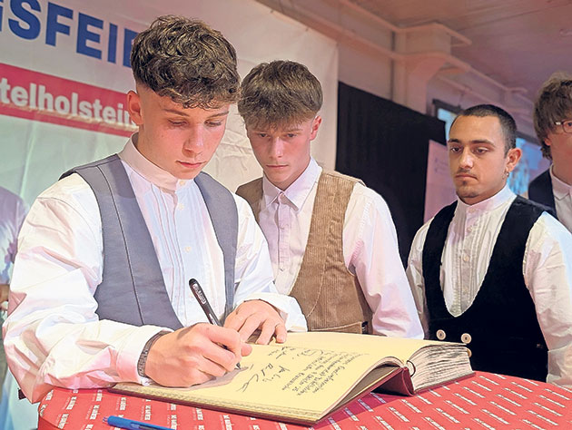 Feierliches Unterschreiben eines Buches bei einer Zeremonie Junge Männer in traditioneller Kleidung bei einer Zeremonie.