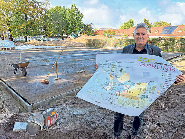 Projektplan für neuen Spielplatz Mann mit Plan vor Baustelle eines Spielplatzes.