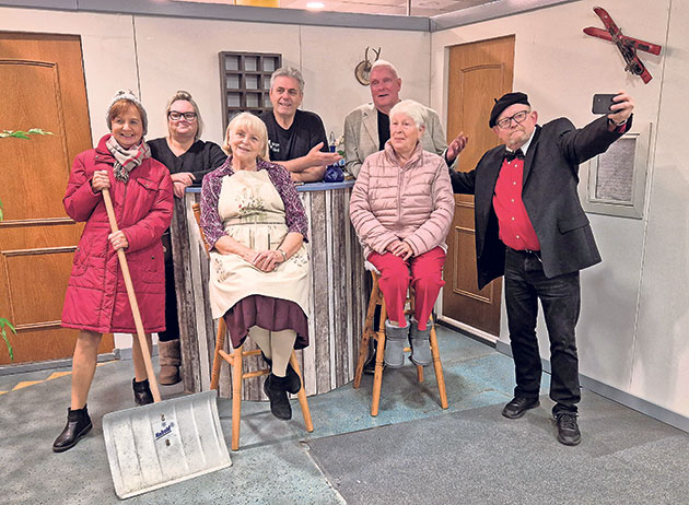 Gruppe von sieben Personen posiert fröhlich in einem Raum.
