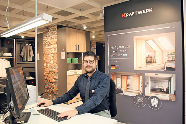 Mann sitzt an einem Schreibtisch im Showroom von KRAFTWERK.