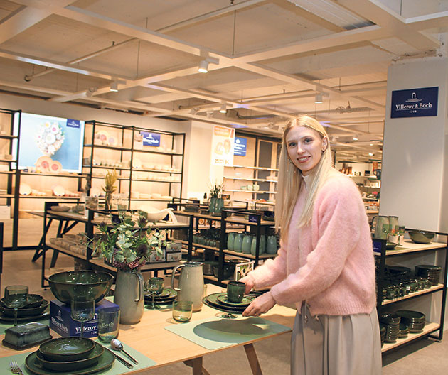 Frau arrangiert Geschirr in einem Geschäft.