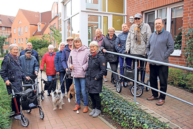 Gruppe von Senioren und Hunden vor einem Gebäude