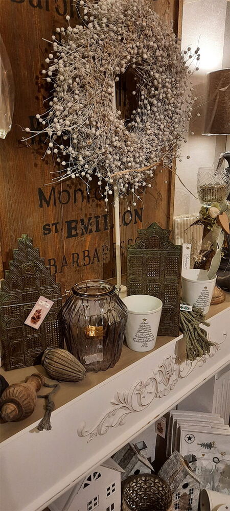 Gemütliches Regal mit Kranz, Kerzen und Deko.