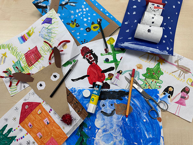 Bunte Kinderzeichnungen und Bastelarbeiten auf einem Tisch.