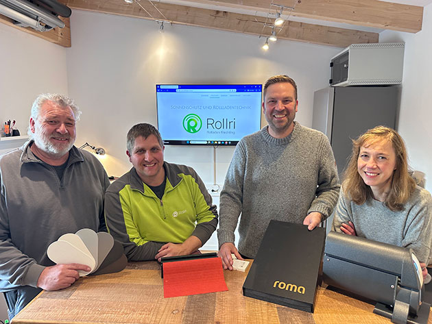 Vier Personen mit Musterkatalogen in einem Büro.