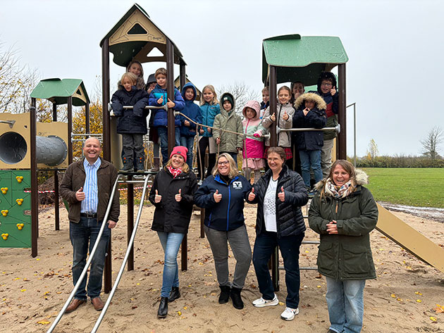Kinder und Erwachsene posieren auf einem Spielplatz.