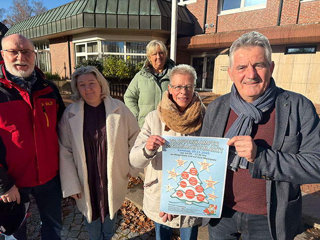 Fünf Personen halten ein Weihnachtsmarkt-Plakat.