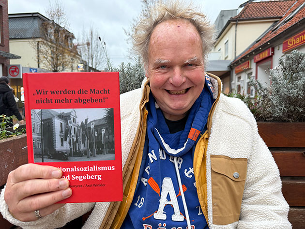 Mann hält Buch über Nationalsozialismus in Bad Segeberg.