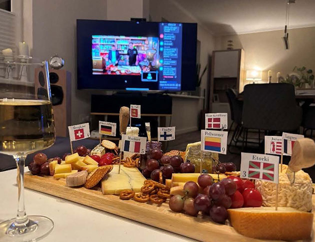 Käseplatte und Wein vor einem Fernseher im Wohnzimmer.