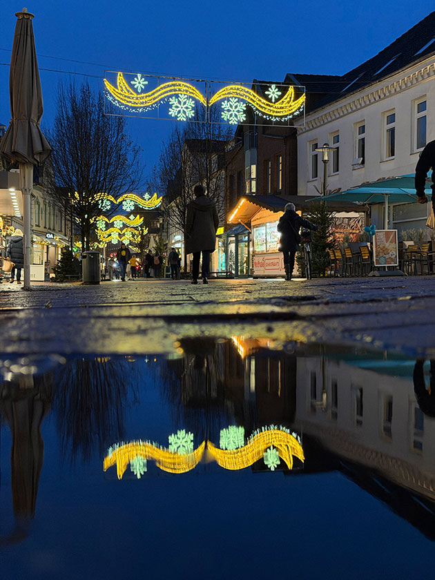 Lichterdekoration in der Straße mit Spiegelung in einer Pfütze.