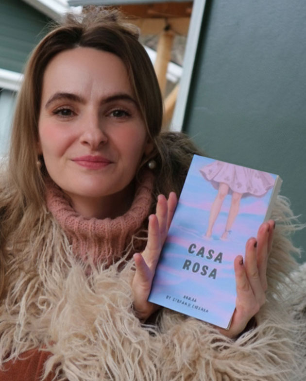 Frau hält ein Buch mit dem Titel 'Casa Rosa'.